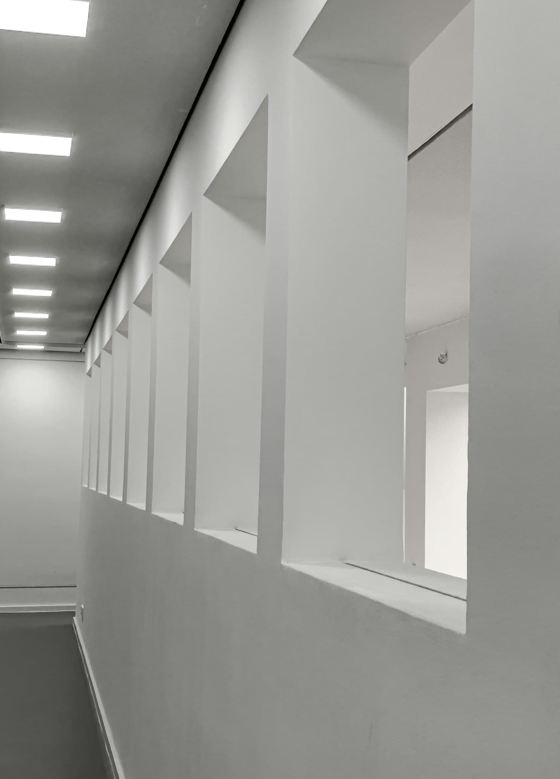 Modern white hallway with square openings and ceiling lights