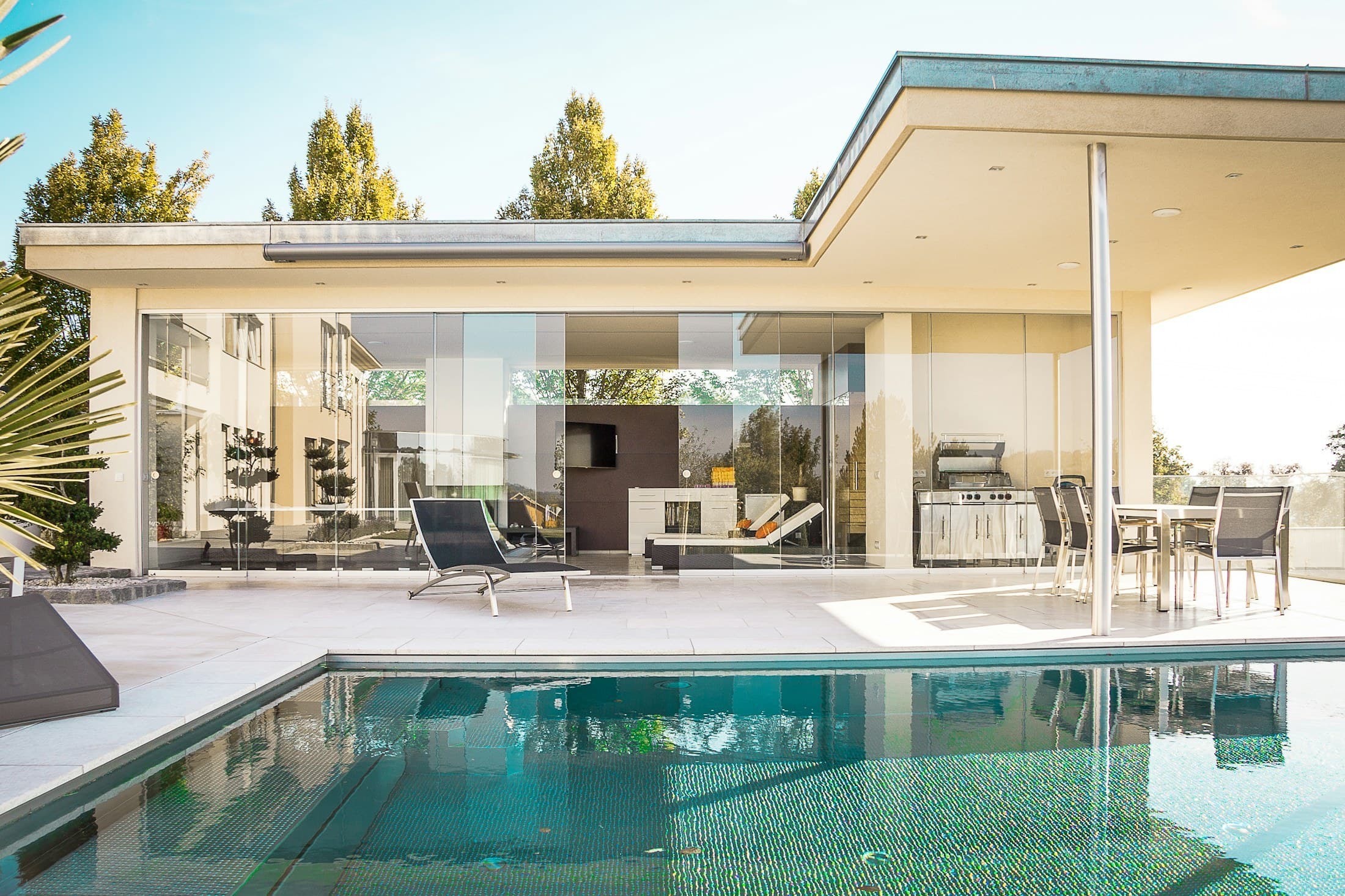 A modern house with glass walls beside a swimming pool on a sunny day